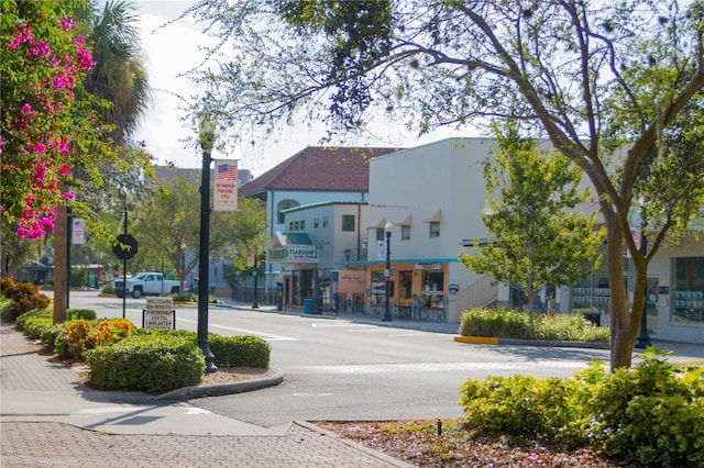 view of road featuring traffic signs, curbs, sidewalks, and street lights