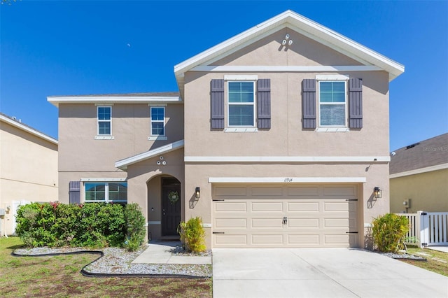 traditional home with a garage, driveway, fence, and stucco siding