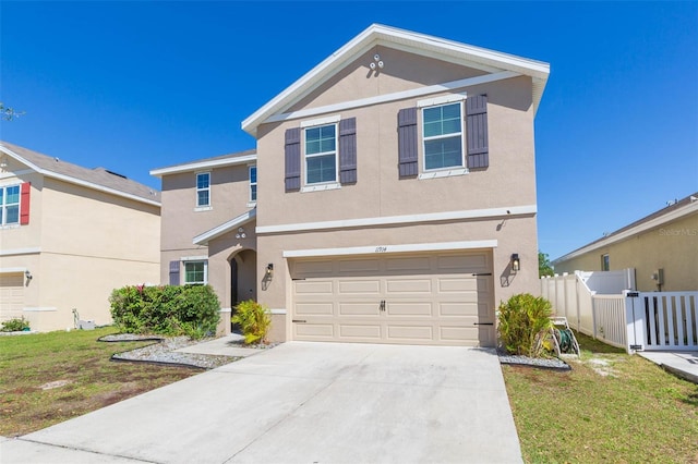 traditional-style home featuring fence, a front lawn, concrete driveway, and stucco siding