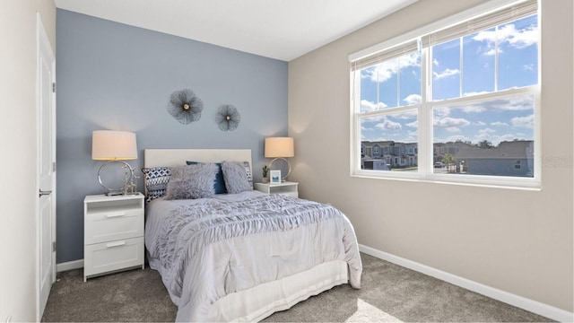 bedroom with dark colored carpet and baseboards