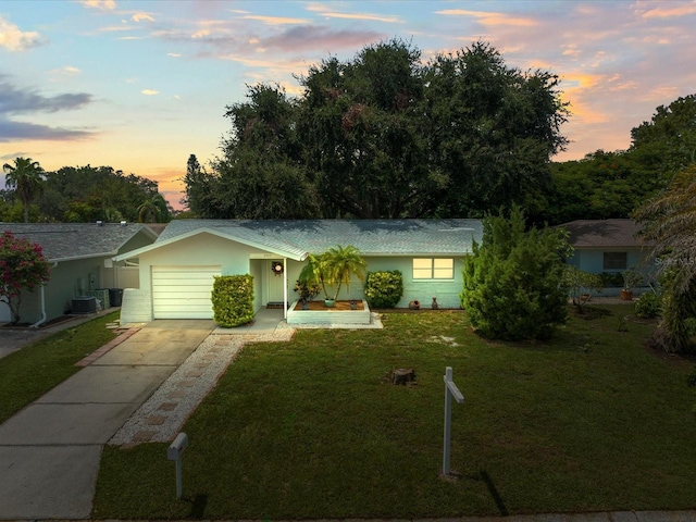 ranch-style house featuring a garage, a yard, central AC, and driveway