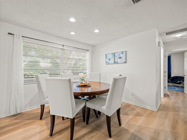 dining room with light wood-style floors, recessed lighting, a textured ceiling, and baseboards