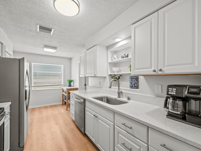 kitchen featuring appliances with stainless steel finishes, visible vents, white cabinets, and a sink