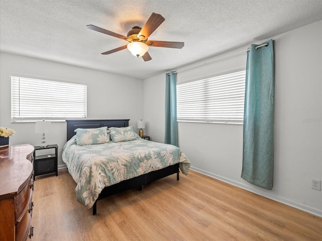 bedroom with light wood-style floors, ceiling fan, multiple windows, and a textured ceiling