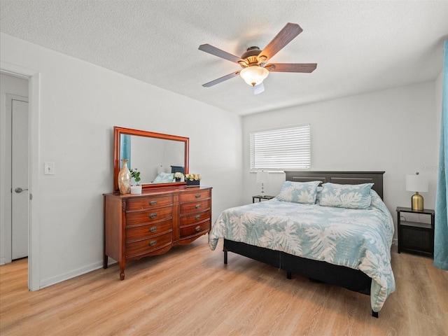 bedroom with a ceiling fan, baseboards, light wood-style flooring, and a textured ceiling