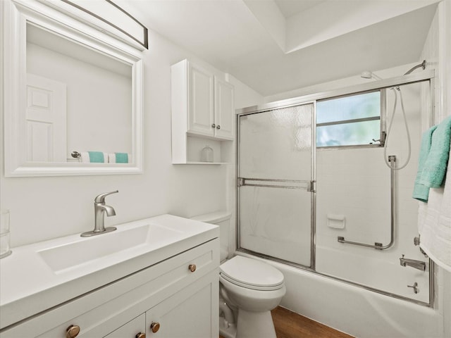 full bathroom with toilet, bath / shower combo with glass door, wood finished floors, and vanity