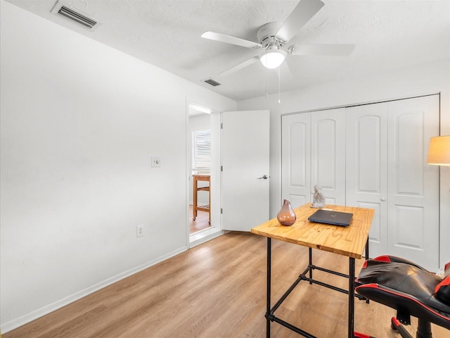 office area featuring baseboards, visible vents, a textured ceiling, and light wood finished floors