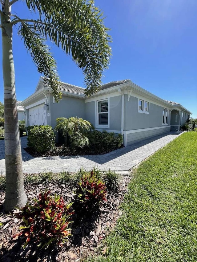 view of home's exterior featuring stucco siding, a lawn, and a garage