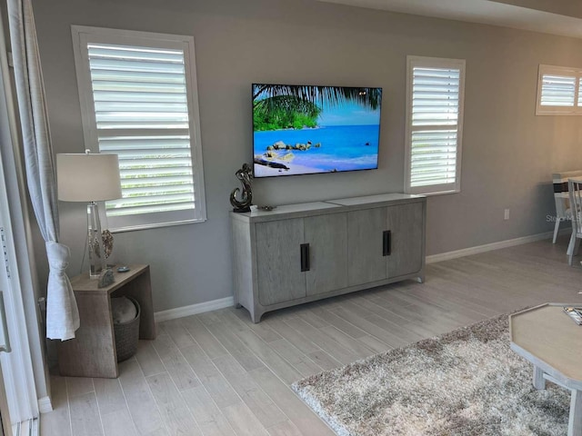 living area with a wealth of natural light, light wood-style flooring, and baseboards