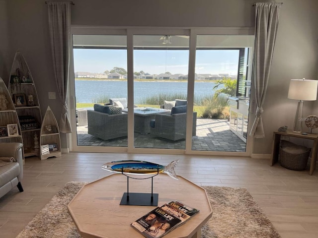 living area with baseboards, a water view, and wood finished floors