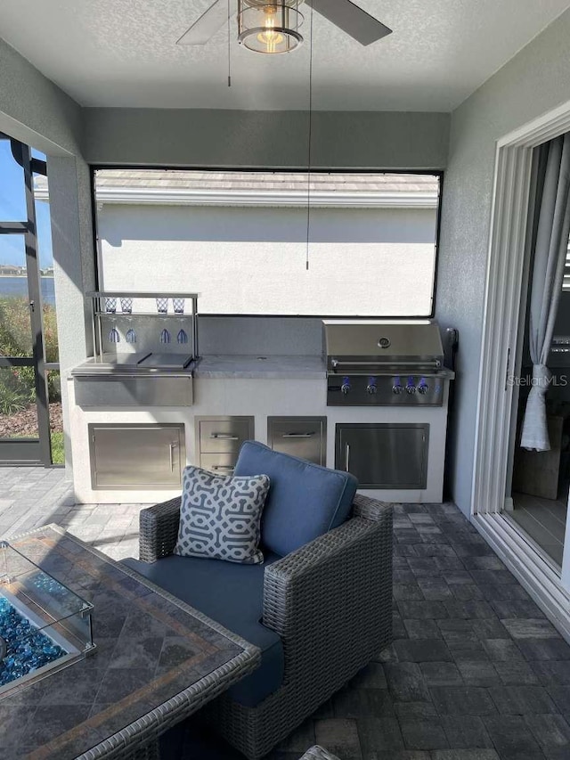 view of patio with area for grilling, glass enclosure, grilling area, and ceiling fan