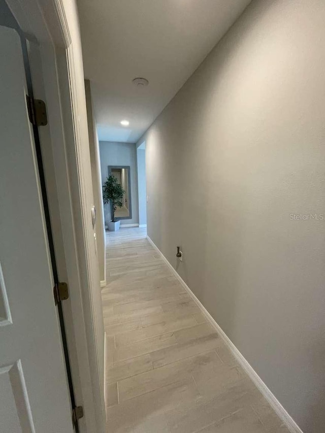 corridor with light wood-style flooring and baseboards