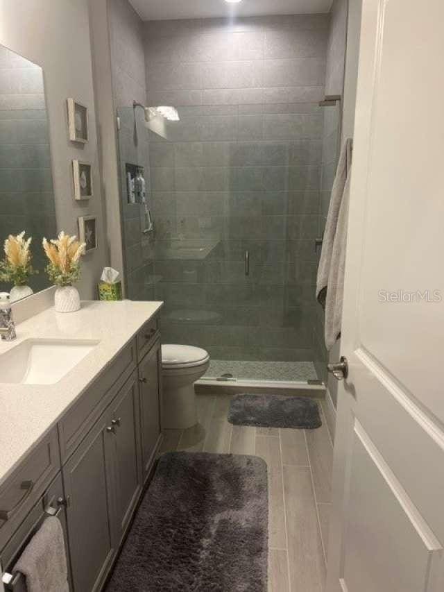 bathroom with a shower stall, toilet, vanity, and wood tiled floor