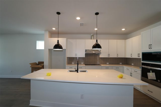 kitchen featuring visible vents, decorative backsplash, a sink, oven, and under cabinet range hood