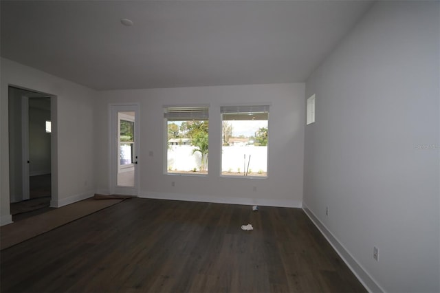 unfurnished room featuring a wealth of natural light, dark wood finished floors, and baseboards