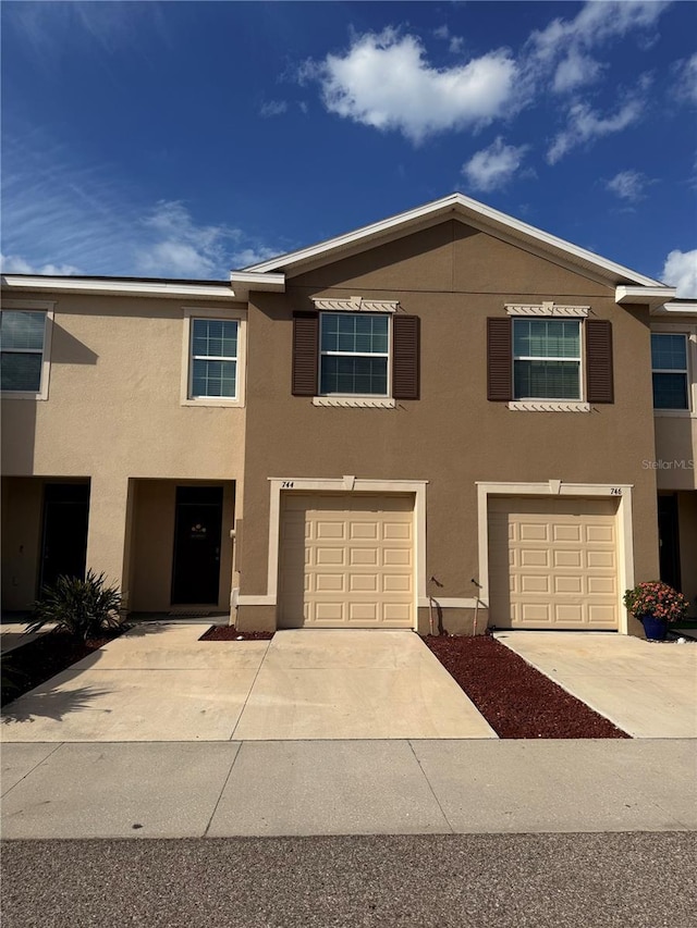 townhome / multi-family property with stucco siding, a garage, and driveway