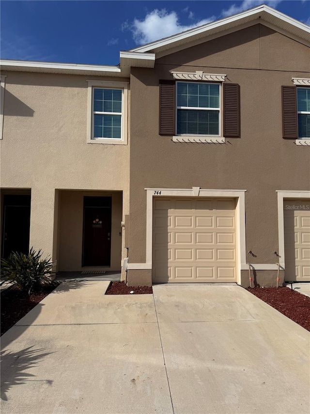 multi unit property with stucco siding, driveway, and an attached garage