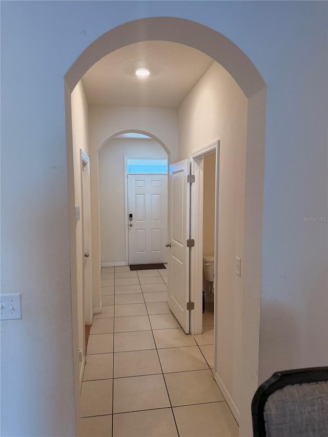 hall featuring light tile patterned floors and baseboards