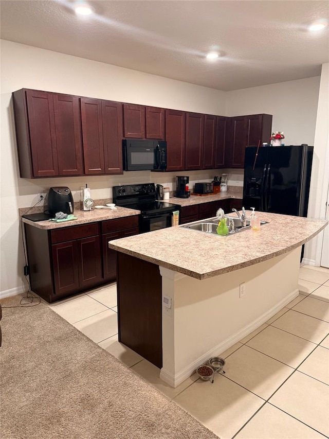 kitchen with a sink, black appliances, light countertops, and light tile patterned floors