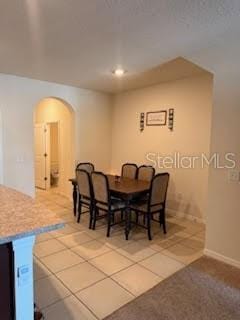 dining space with tile patterned floors and arched walkways