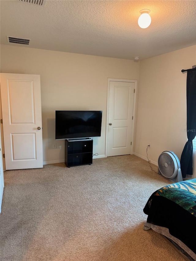 unfurnished bedroom featuring visible vents, a textured ceiling, and carpet flooring