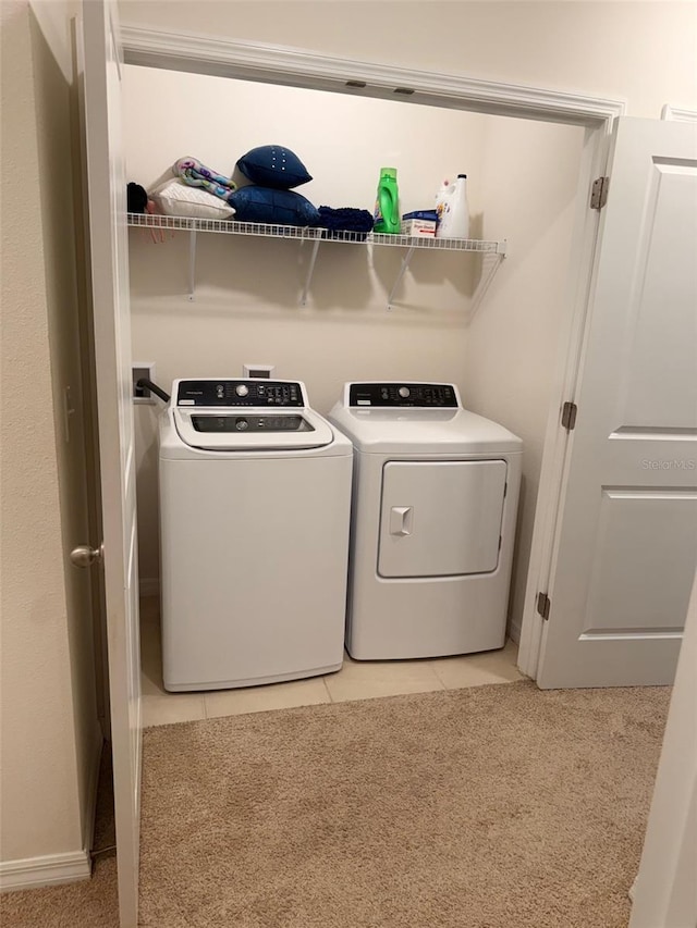 laundry room with light tile patterned flooring, laundry area, washing machine and dryer, and light colored carpet