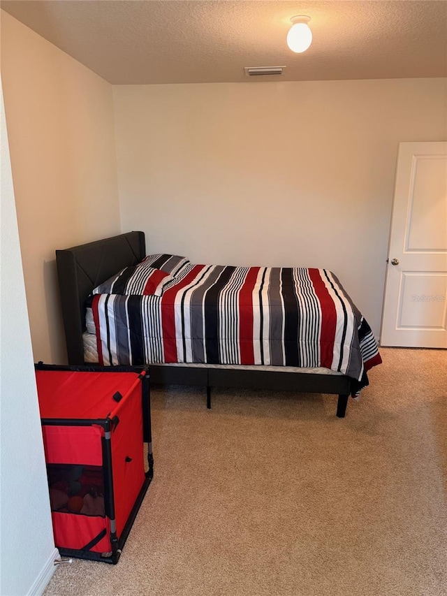 bedroom with visible vents, carpet floors, and a textured ceiling