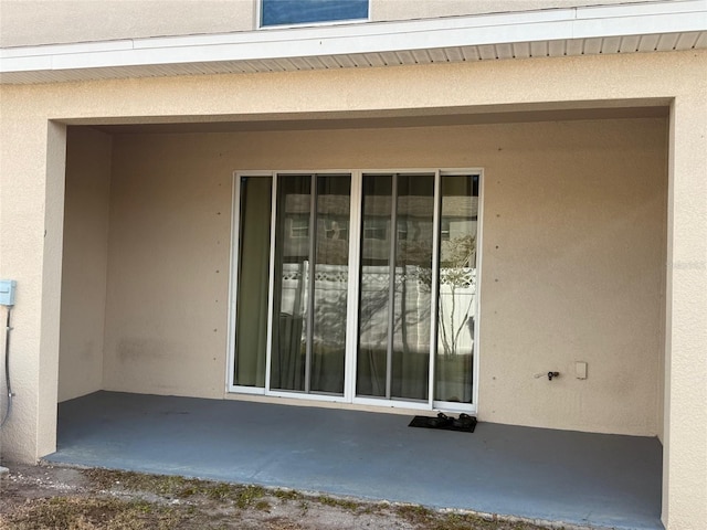 doorway to property featuring a patio and stucco siding