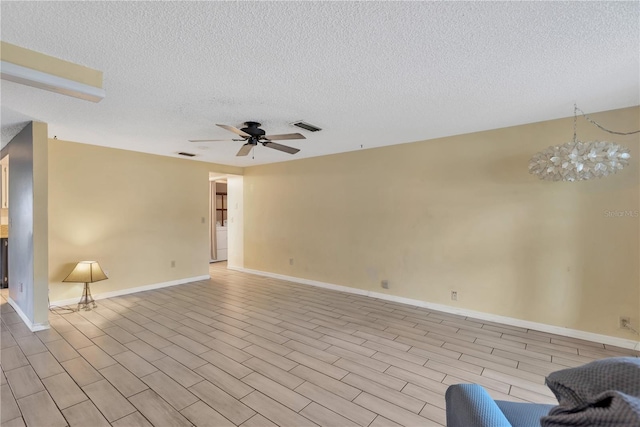 unfurnished living room with visible vents, light wood-style flooring, ceiling fan with notable chandelier, a textured ceiling, and baseboards