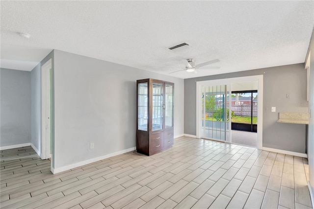 unfurnished room with baseboards, visible vents, a textured ceiling, and a ceiling fan