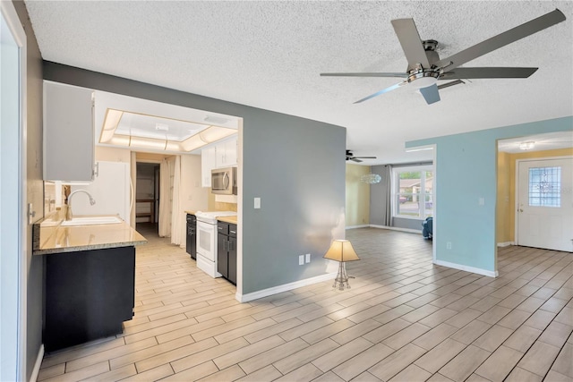 kitchen featuring open floor plan, light countertops, light wood-style flooring, white appliances, and a sink