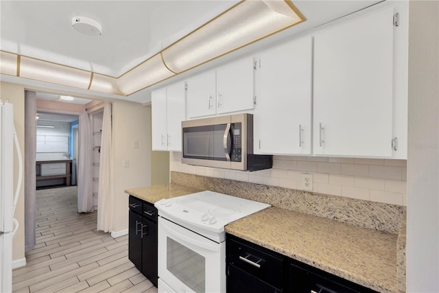 kitchen featuring white appliances, dark cabinetry, light wood-style floors, white cabinetry, and backsplash