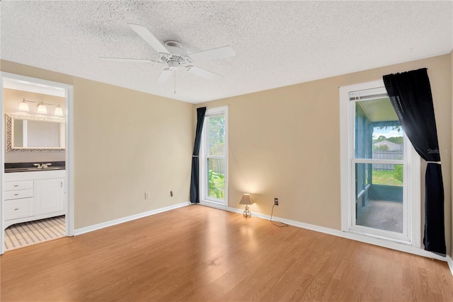 interior space with a sink, a textured ceiling, and light wood-style flooring