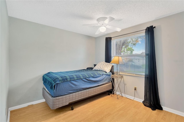 bedroom with light wood finished floors, ceiling fan, a textured ceiling, and baseboards