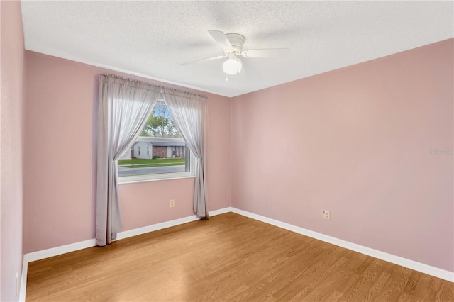 unfurnished room with ceiling fan, a textured ceiling, baseboards, and wood finished floors