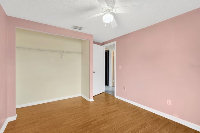 unfurnished bedroom with visible vents, wood finished floors, a closet, baseboards, and ceiling fan