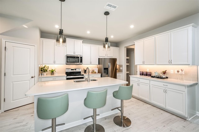 kitchen featuring appliances with stainless steel finishes, a breakfast bar, white cabinetry, and a sink