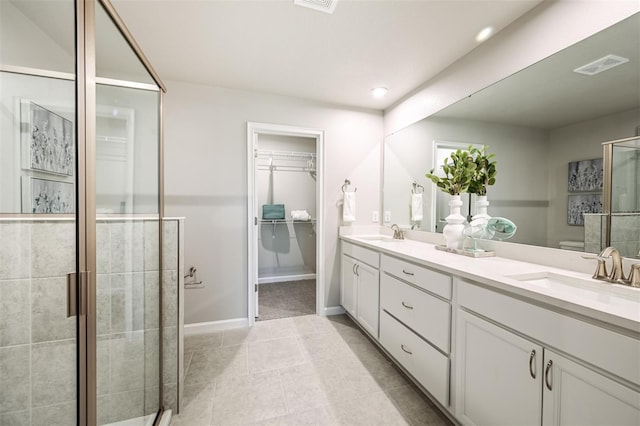 bathroom with double vanity, a shower stall, visible vents, and a sink