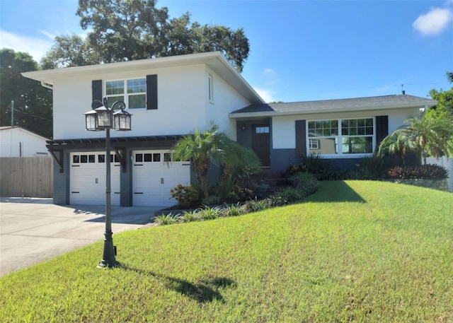 split level home with fence, driveway, stucco siding, a front lawn, and a garage