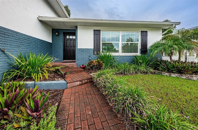 entrance to property featuring brick siding and stucco siding