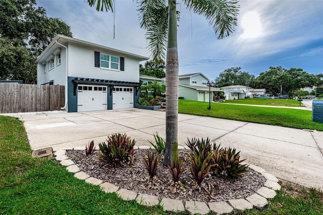 view of front of house with a front yard, fence, an attached garage, stucco siding, and concrete driveway