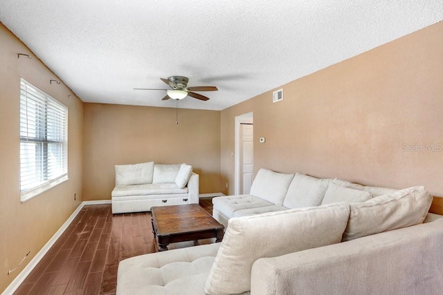 living area featuring baseboards, visible vents, a ceiling fan, wood finished floors, and a textured ceiling