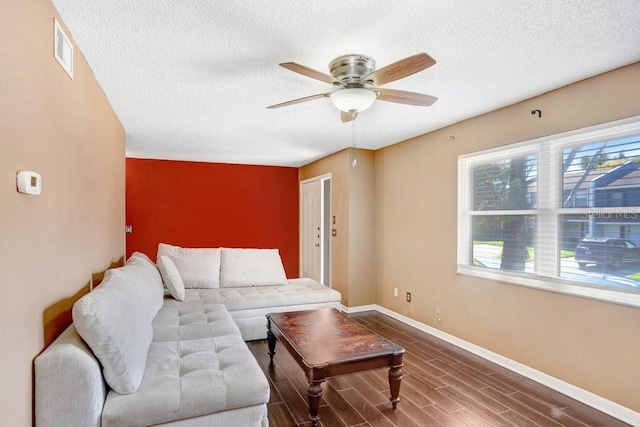 living room featuring visible vents, baseboards, a ceiling fan, wood finished floors, and a textured ceiling