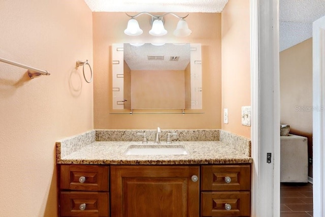 bathroom featuring a textured ceiling, tile patterned flooring, and vanity