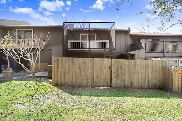 back of house with a yard, fence, a balcony, and central air condition unit