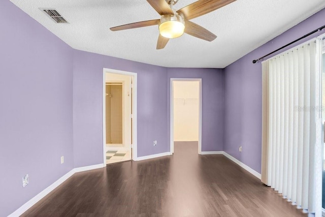 unfurnished room featuring a textured ceiling, wood finished floors, a ceiling fan, visible vents, and baseboards