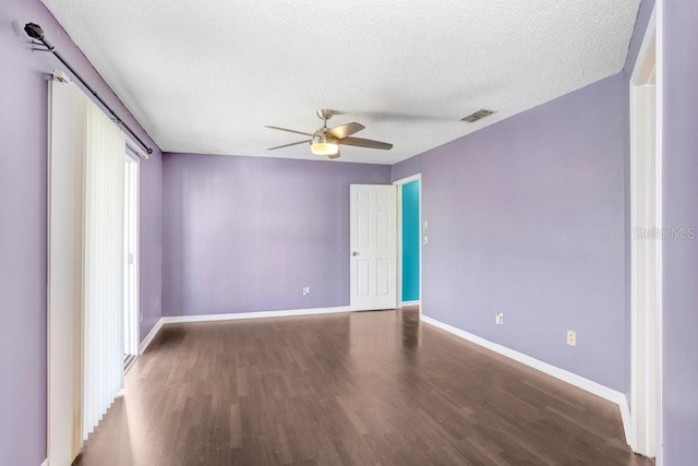 empty room featuring a textured ceiling, wood finished floors, visible vents, and baseboards