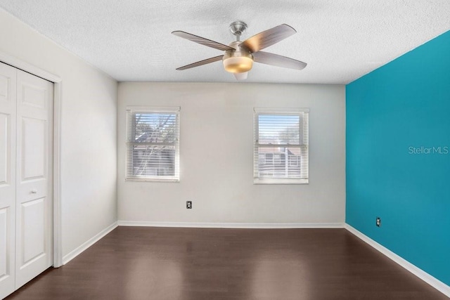 unfurnished bedroom featuring multiple windows, baseboards, and dark wood-type flooring