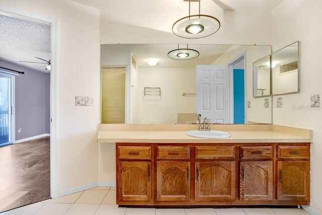 bathroom with tile patterned flooring, baseboards, a textured ceiling, and vanity