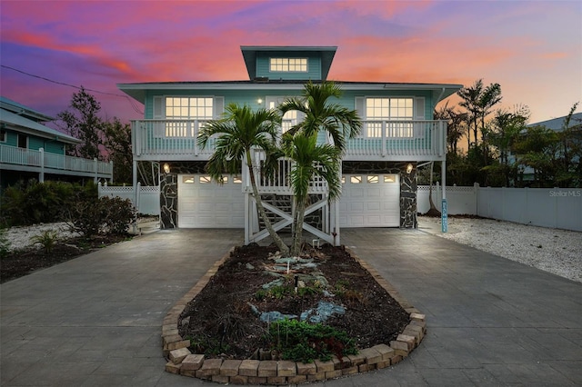 coastal inspired home featuring fence, a garage, and driveway